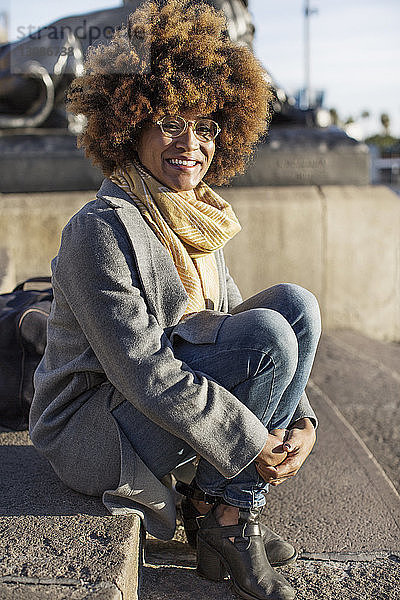 Porträt einer glücklichen Frau  die auf Stufen in der Stadt sitzt