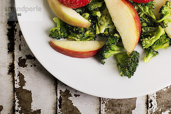 Draufsicht auf Brokkoli und Äpfel im Teller auf dem Tisch