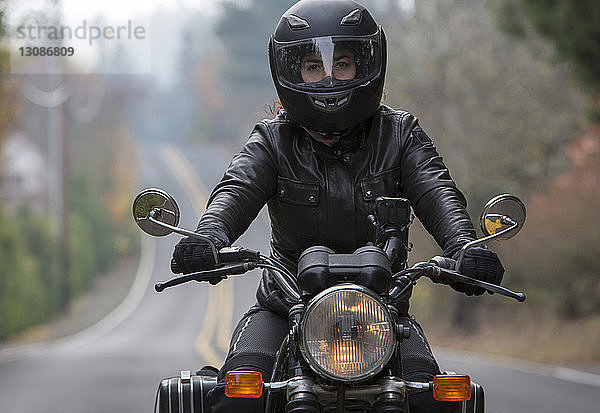 Weibliche Motorradfahrerin mit Sturzhelm beim Motorradfahren auf der Straße