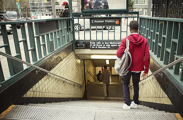 Rückansicht eines Studenten  der in der U-Bahn die Stufen hinuntergeht