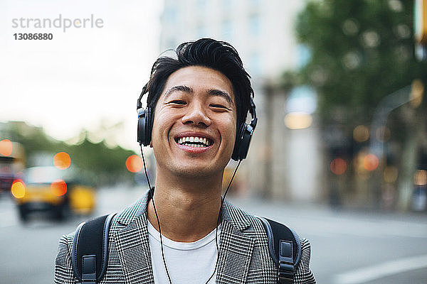 Porträt eines glücklichen Geschäftsmannes  der in der Stadt Musik hört