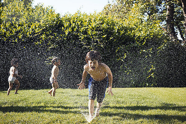 Zwei Jungen spielen im Sprinkler