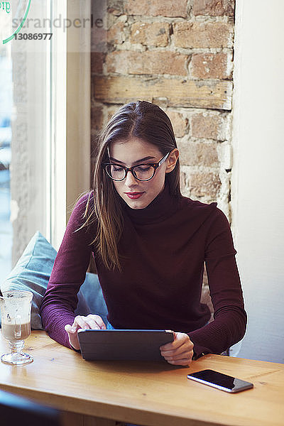 Frau benutzt Tablet-Computer  während sie im Café sitzt