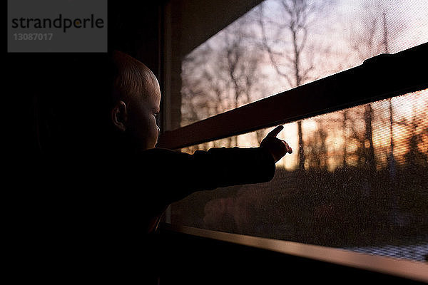 Kleiner Junge schaut durchs Fenster  während er in der Dunkelkammer steht