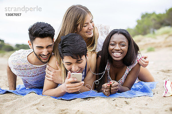Fröhliche Frau liegt auf Freunden am Strand