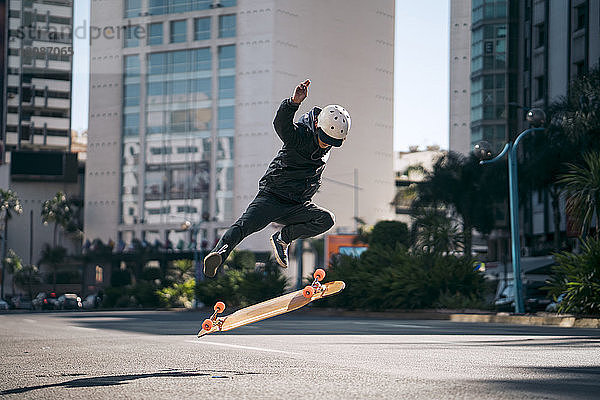 Mann führt Stunt beim Skateboardfahren auf der Straße in der Stadt aus