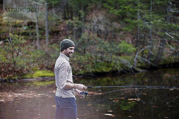 Lächelnder Mann beim Angeln im See im Wald