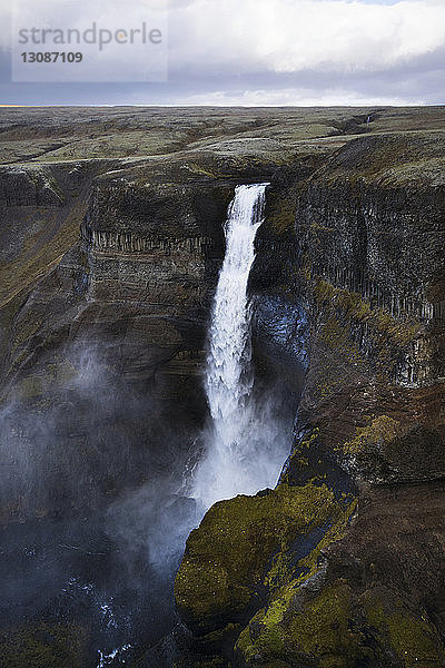 Szenische Ansicht des Haifoss-Wasserfalls vor einer Wolkenlandschaft