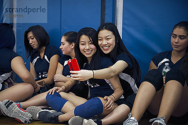 Teenager-Mädchen klicken beim Entspannen auf dem Volleyballfeld auf Selfie