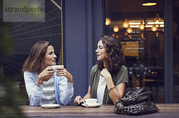 Freundinnen unterhalten sich bei einem Kaffee im Straßencafé