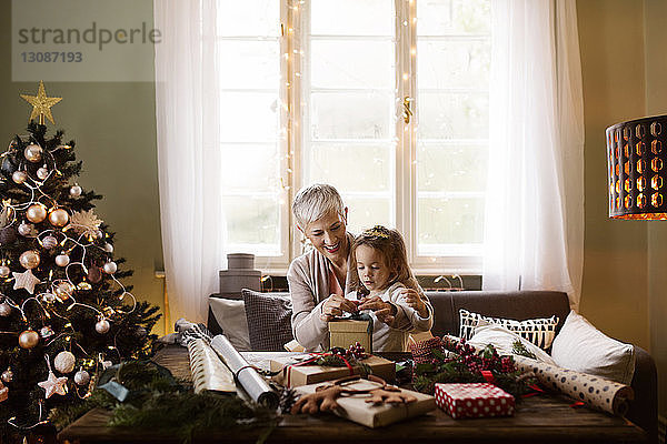 Großmutter hilft Mädchen beim Packen von Geschenken zu Weihnachten