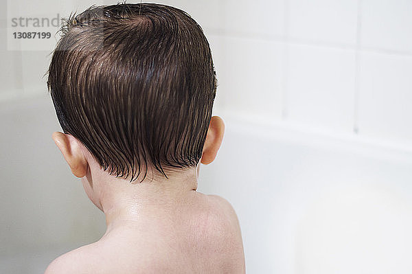 Rückansicht eines Jungen ohne Hemd in der Badewanne zu Hause