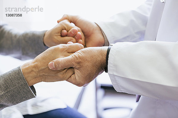 Nahaufnahme eines Arztes  der die Hände eines älteren Patienten hält