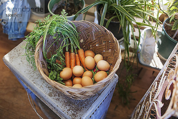 Draufsicht auf Eier und Gemüse im Korb auf dem Tisch im Gewächshaus
