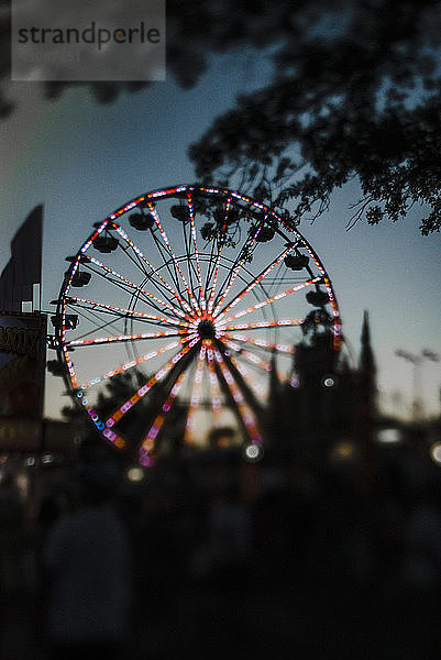 Beleuchtetes Riesenrad in der Abenddämmerung im Vergnügungspark gegen den Himmel