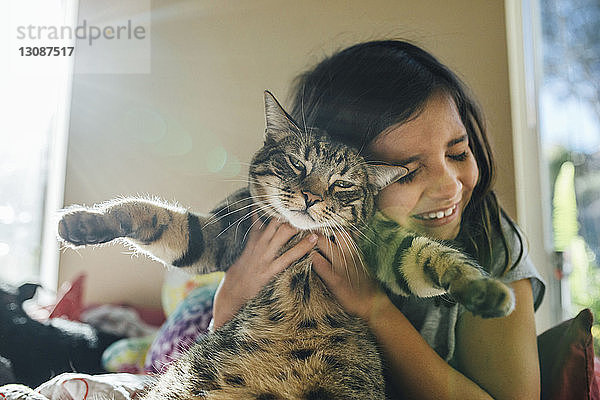 Glückliches Mädchen mit Katze im Bett zu Hause