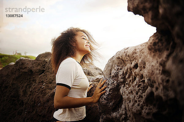 Seitenansicht eines Teenagers  der an einer Felsformation vor klarem Himmel steht