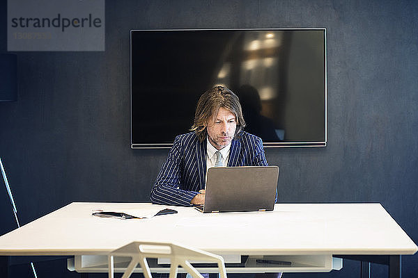 Reifer Geschäftsmann mit Laptop-Computer im Büro