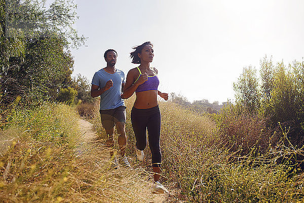 Mann und Frau joggen auf einem Grasfeld