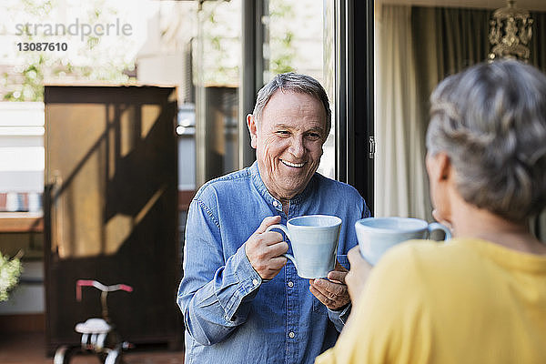 Glückliches älteres Ehepaar trinkt Kaffee auf der Veranda