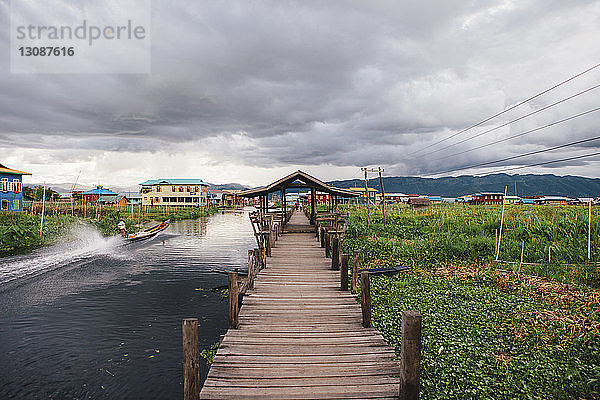 Fussgängerbrücke am Inle-See und Feld gegen bewölkten Himmel