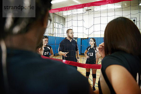 Erfahrener männlicher Trainer erklärt Mannschaft auf Volleyballfeld