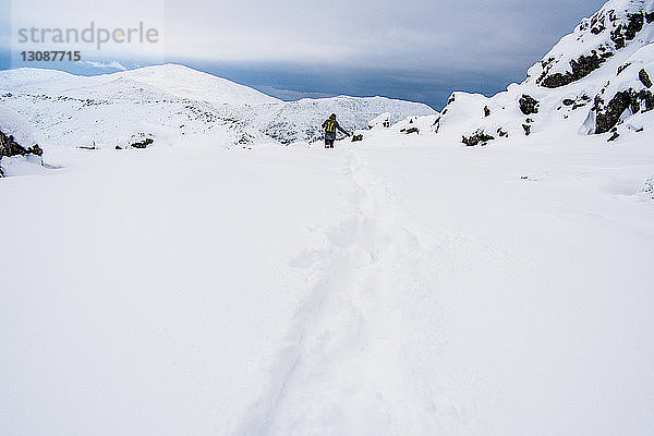 Fernansicht eines Wanderers auf einem schneebedeckten Berg gegen den Himmel