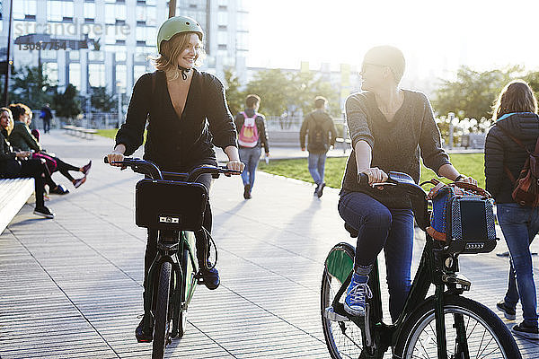 Lächelnde Freunde beim Fahrradfahren auf der Stadtstraße