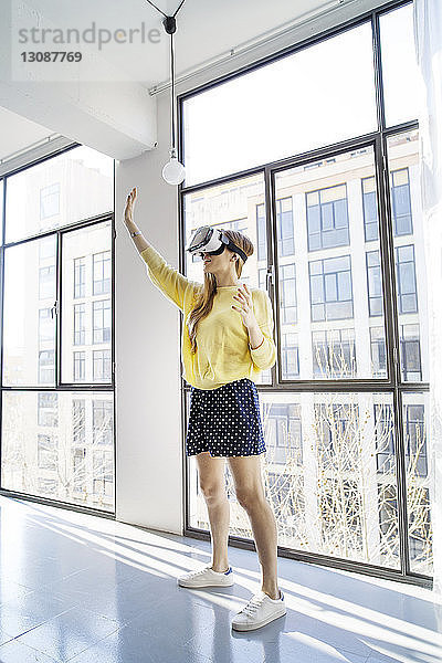 Geschäftsfrau benutzt Virtual-Reality-Simulator  während sie im Büro am Fenster steht