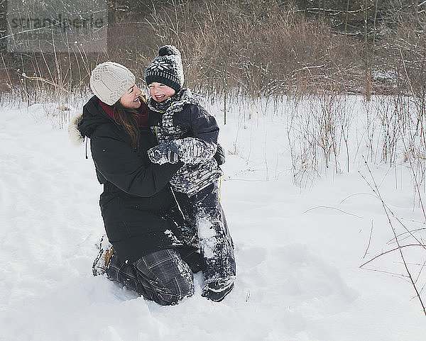 Fröhliche Mutter und Sohn auf verschneitem Feld
