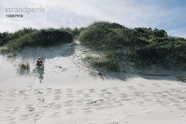 Junge spielt im Sommer am Strand im Sand