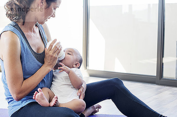 Mutter füttert Säugling  während sie zu Hause am Fenster sitzt