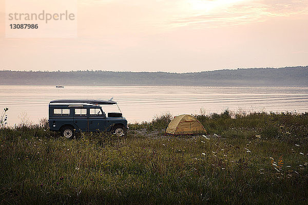 Auto und Zelt am See bei Sonnenaufgang