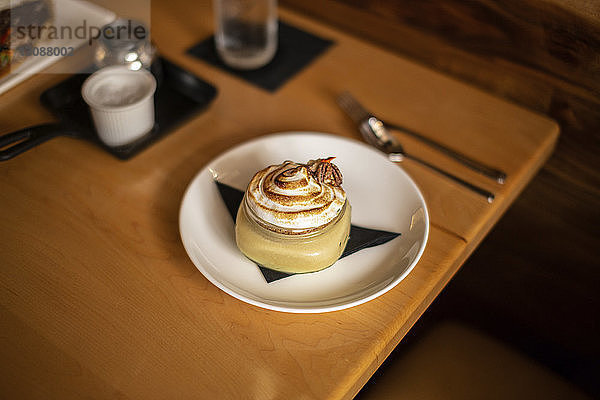 Hochwinkelansicht eines Desserts  das in einem Teller auf einem Holztisch serviert wird