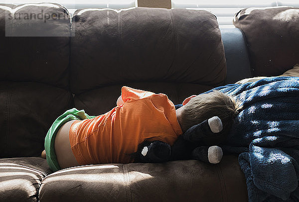Rückansicht eines Jungen  der sich zu Hause auf dem Sofa entspannt