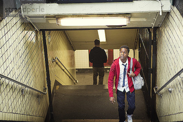 Schüler in voller Länge in Schuluniform  der von der U-Bahn nach oben geht