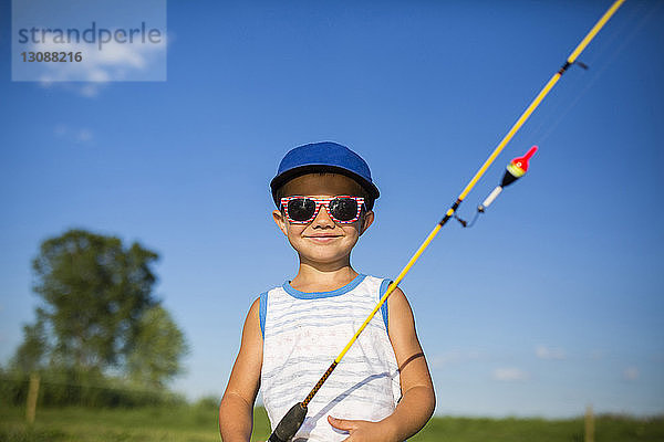 Bildnis eines Jungen mit Angelrute auf Feld gegen Himmel stehend