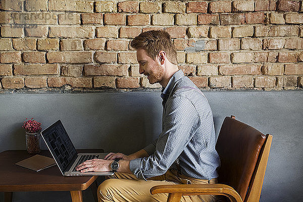 Seitenansicht eines kreativen Geschäftsmannes mit Laptop in der Hotellobby