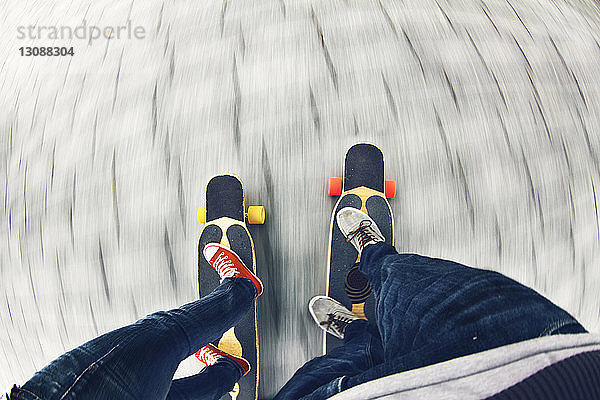 Niedriger Abschnitt eines Paares beim Skateboarden auf der Straße