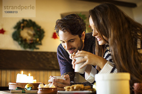 Lächelndes Paar trinkt an Weihnachten Kaffee bei Tisch