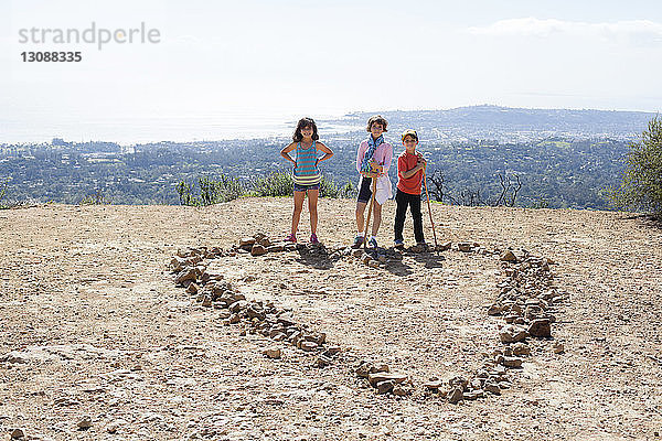 Porträt von Geschwistern auf Berg vor klarem Himmel stehend