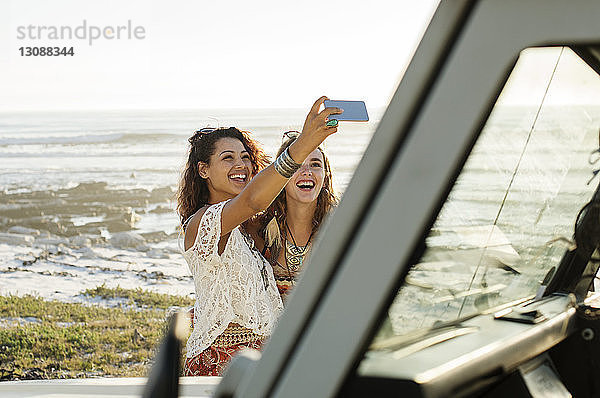 Glückliche Freundinnen  die sich beim Stehen im Geländewagen am Strand selbstständig machen
