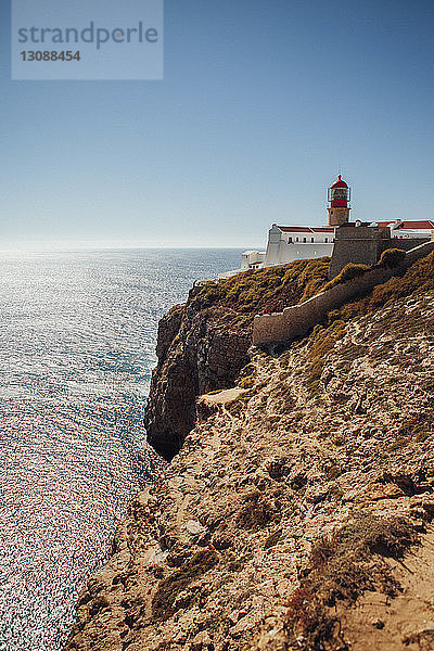 Leuchtturm auf Klippe am Meer vor klarem Himmel