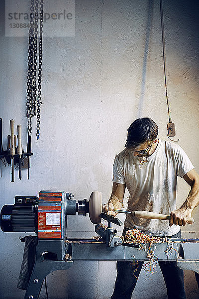 Schreiner hält Meißel beim Formen einer Holzschüssel in der Werkstatt