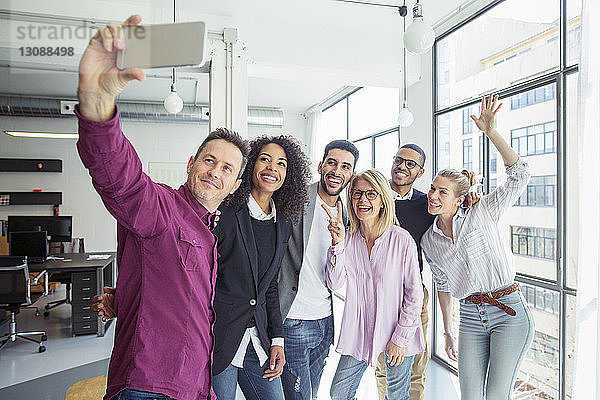 Fröhliche Geschäftsleute  die sich im Büro am Fenster stehen