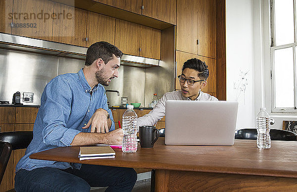 Geschäftsleute im Gespräch mit Laptop-Computern im Kreativbüro