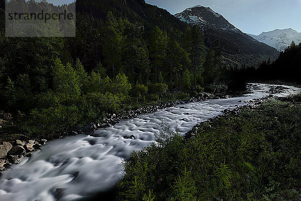 Fluss inmitten des Waldes gegen den Himmel in der Abenddämmerung