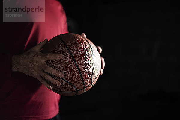 Ein Mann hält nachts Basketball in der Mitte