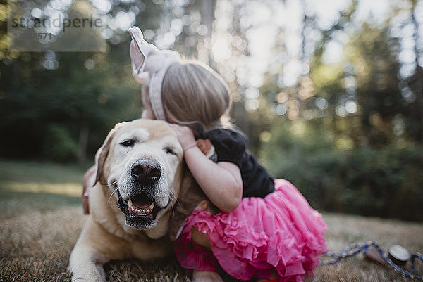 Verspieltes Mädchen umarmt Hund auf dem Feld