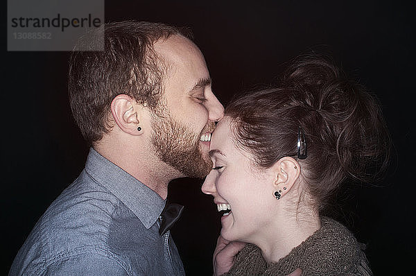 Seitenansicht des glücklichen Paares vor schwarzem Hintergrund